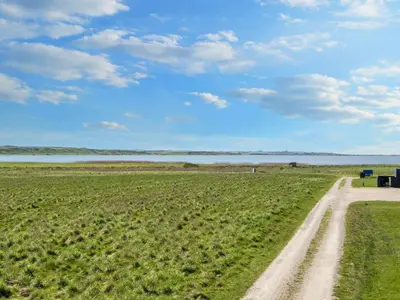 a dirt road in a field next to a body of water at Luxury Retreat by the Sea - By Traum Ferienwohnungen in Harboør