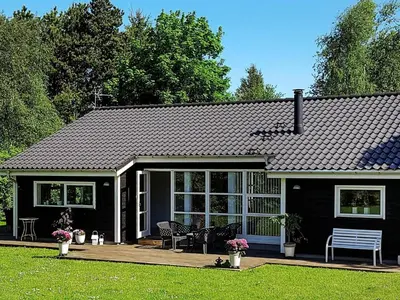 a black house with a porch and a bench at 10 person holiday home in Løgstør-By Traum in Trend