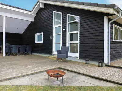 a black house with a patio with chairs and a table at 10 person holiday home in Løgstør-By Traum in Trend