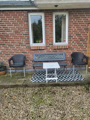 a bench and two chairs in front of a brick building at Astrup vig Spa og Sauna in Roslev