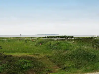 a dirt road in a field with the ocean in the background at 8 person holiday home in Løgstør-By Traum in Trend