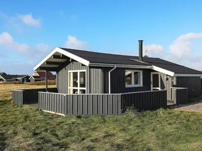 a small black and white house on a field at Seaside Fun & Relaxation-By Traum in Harboør