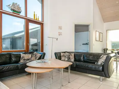 a living room with a black leather couch and a table at 8 person holiday home in Ulfborg-By Traum in Thorsminde