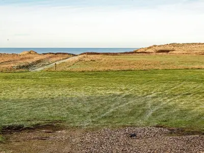 a field of grass with the ocean in the background at 6 person holiday home in Lemvig-By Traum in Trans