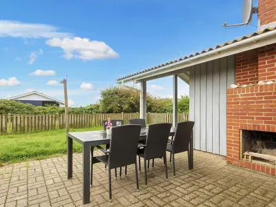 a table and chairs on a patio with a fireplace at Cozy Renovated Cottage - By Traum Ferienwohnungen in Harboør