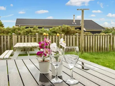 a table with two wine glasses and flowers on it at Cozy Renovated Cottage - By Traum Ferienwohnungen in Harboør