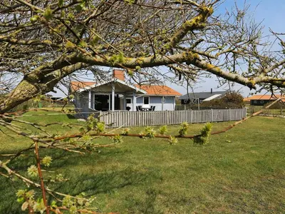 a white house with a fence in a yard at Cozy Renovated Cottage - By Traum Ferienwohnungen in Harboør