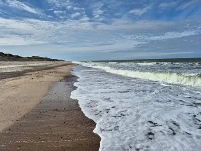 an empty beach with waves crashing on the shore at Cozy Renovated Cottage - By Traum Ferienwohnungen in Harboør