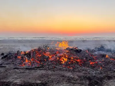 a bonfire on the beach at sunset at 8 person holiday home in Pandrup-By Traum in Blokhus