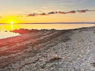 a beach with the sun setting over the water at 6 person holiday home in Spøttrup-By Traum in Lihme