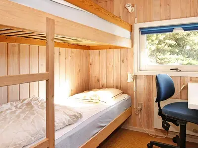 a bedroom with two bunk beds and a desk at 6 person holiday home in Blokhus-By Traum in Blokhus
