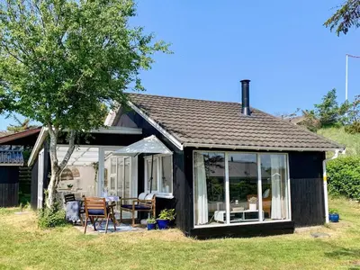 a small house with a table and chairs in the yard at 4 person holiday home in Blokhus-By Traum in Blokhus