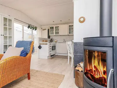 a living room with a fireplace and a kitchen at 4 person holiday home in Blokhus-By Traum in Blokhus