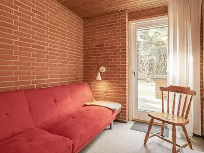 a red couch in a room with a brick wall at 6 person holiday home in Hurup Thy-By Traum in Sindrup