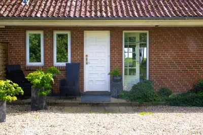 a brick house with a white door and two chairs at Dejligt og stort hus med spa og sauna in Roslev