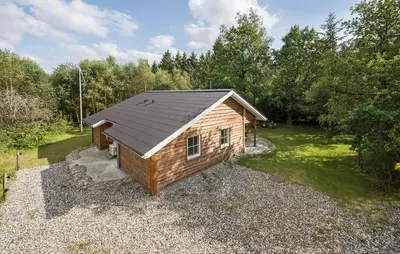 a small cabin with a black roof on a gravel yard at 3 Bedroom Gorgeous Home In Skals in Skals