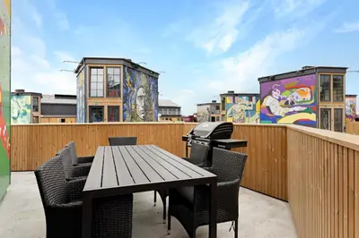 a patio with a wooden table and chairs on a balcony at Stort sommerhus - Legeland for store og små in Pandrup