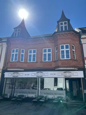 a large brick building with the sun shining on it at Hotel Tante in Lemvig