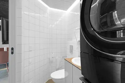 a bathroom with a toilet and a washer and dryer at Funart 4 in Pandrup