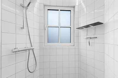 a shower with a window in a white bathroom at Funart 5 in Pandrup