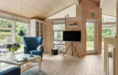 a living room with a tv and a blue chair at 2 Bedroom Cozy Home In Højslev in Højslev