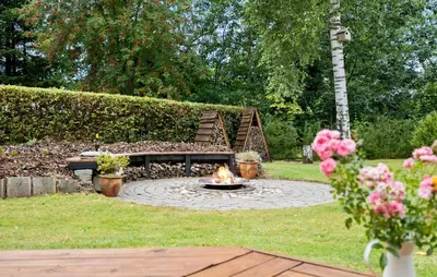 a fire pit in a yard with a bench and flowers at 2 Bedroom Cozy Home In Højslev in Højslev