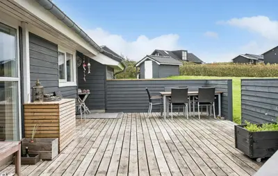 a deck with a table and chairs on a house at Cozy Home In Lemvig With Sauna in Lemvig