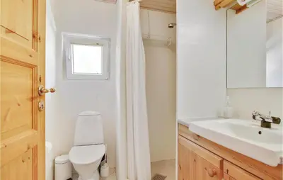 a bathroom with a toilet and a sink and a mirror at Holiday Home Blokhus With Sauna 156 in Blokhus