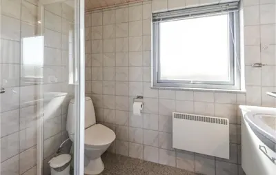 a bathroom with a toilet and a sink and a window at Holiday Home Vestervig With A Fireplace 164 in Vestervig