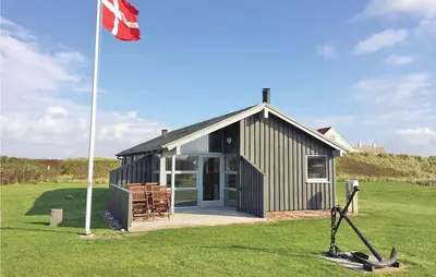 a building with a flag in the grass at Holiday Home Vestervig With A Fireplace 164 in Vestervig