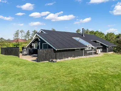a house with a black roof and a yard at Holiday Home Wilmer - 600m from the sea by Interhome in Løkken