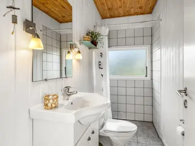 a white bathroom with a sink and a toilet at Holiday Home Wilmer - 600m from the sea by Interhome in Løkken