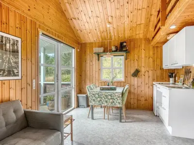 a kitchen and dining room with a table and a couch at Holiday Home Unge - 2-9km from the sea by Interhome in Blokhus