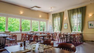 a restaurant with tables and chairs and windows at Morup Mølle Kro in Bedsted Thy
