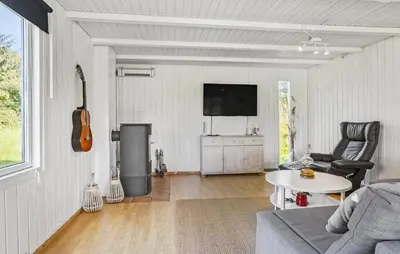 a living room with a couch and a tv and a guitar at 3 Bedroom Beautiful Home In Roslev in Roslev