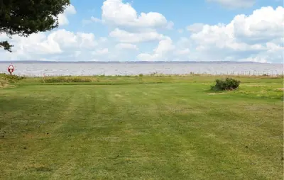 a field of grass with a large body of water at 3 Bedroom Beautiful Home In Thyholm in Thyholm