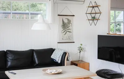 a living room with a black leather couch and a table at 3 Bedroom Beautiful Home In Thyholm in Thyholm