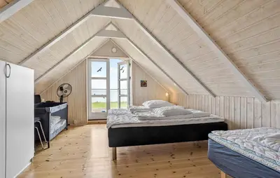 a attic bedroom with two beds and a window at Lovely Home In Fur With Sauna in Fur