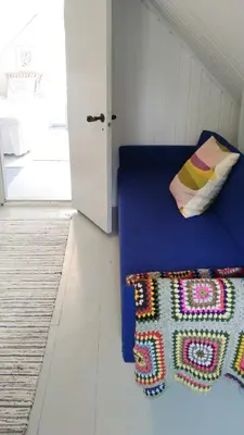a bedroom with a blue bed with a pillow and a rug at Summer House For The Big Family Close To The Fjord in Agger