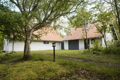 a parking meter in front of a house with a tree at Summer House For The Big Family Close To The Fjord in Agger
