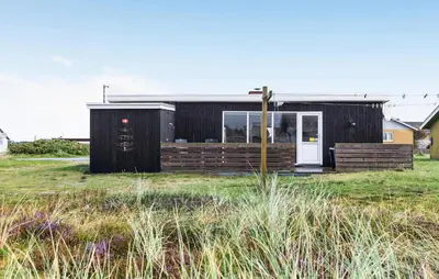 a black house with a white door in a field at 2 Bedroom Nice Home In Thisted in Thisted