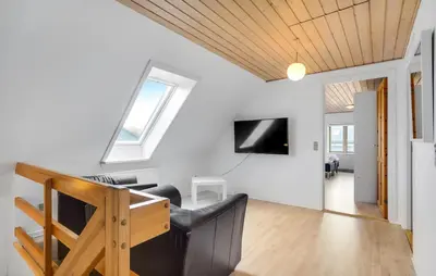 a living room with a couch and a tv on a wall at Det gamle forsamlinghus in Struer