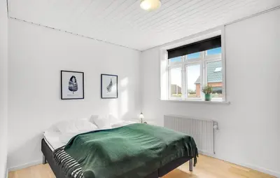 a white bedroom with a bed and a window at Det gamle forsamlinghus in Struer