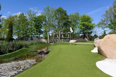 a putting green with a bridge and a creek at Skønt Sommerhus Golfhytte midt i skønne omgivelser in Gatten