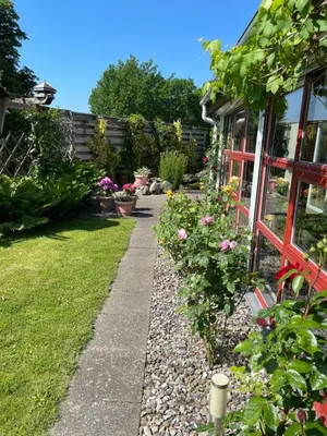 a garden path with flowers and a house at Naturlig Ro in Aalborg