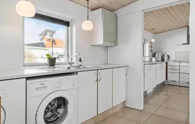 a kitchen with a washing machine in a white kitchen at Lovely Home In Blokhus With Wifi in Blokhus