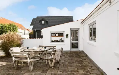 a patio with a table and chairs in front of a white house at Lovely Home In Blokhus With Wifi in Blokhus
