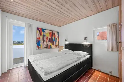 a bedroom with a bed and a painting on the wall at Pool And Activity House With A 180-Degree View Of The North Sea, Located At Lild Strand in Frøstrup