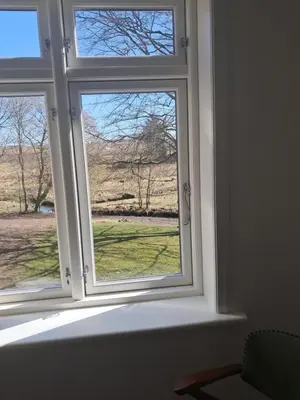 a window with a view of a field through it at Dybvad Mølle bed and breakfast in Års