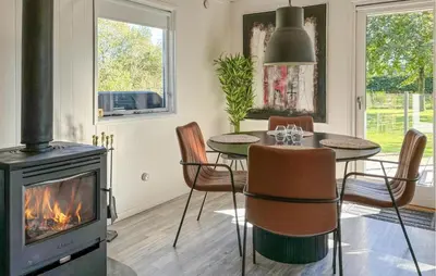 a dining room with a fireplace and a table and chairs at Awesome Home In Hjerm With Wifi in Hjerm
